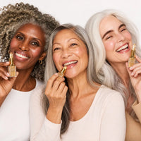 Three smiling mature women with different skin tones wearing Lumi & Luna lipstick