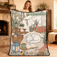 Woman holding the Woodland Retreat coloring blanket design, a cat sleeping in a forest tent scene